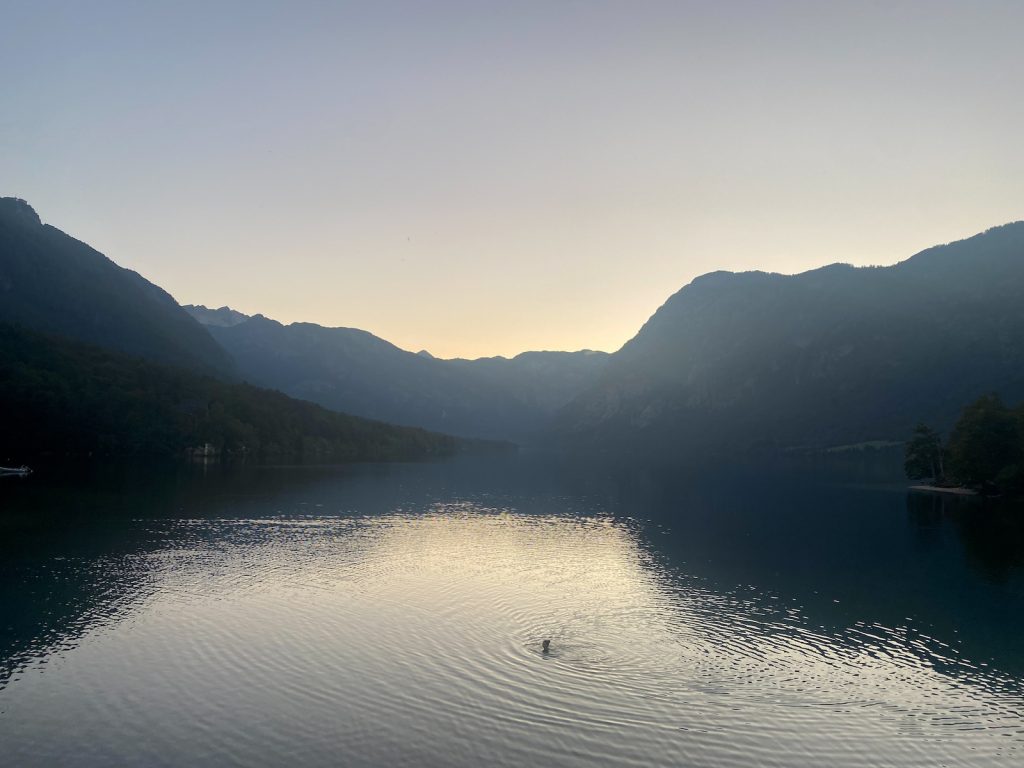 Bohinjsko jezero u suton okruženo planinama.
